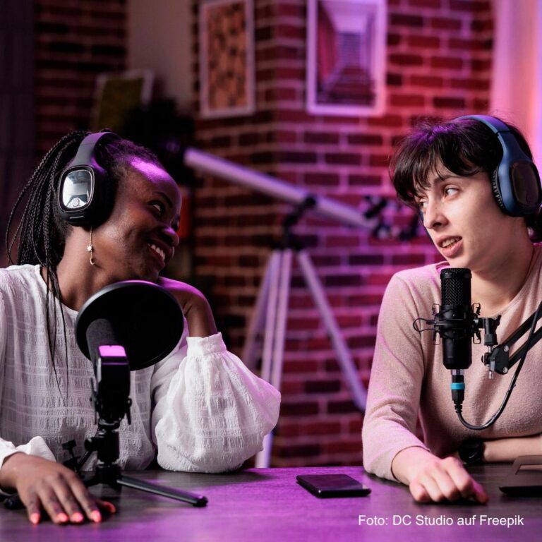 Zwei junge Frauen sitzen im Studio und nehmen einen Podcast auf